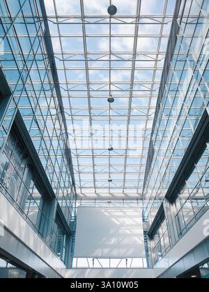 Modern airport terminal interior. Looking up at the sky through a glass roof, white empty banner on the wall. Stock Photo