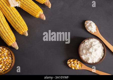 Corn starch in wooden bowl and spoon with dried corn groats, kernels on rustic table. corn ingredients concept Stock Photo