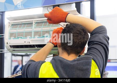 A worker installing an indoor air conditioner unit. Industry Stock Photo