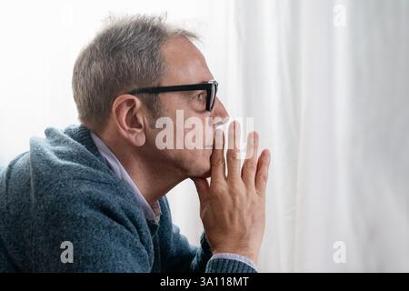 Close-up of a senior man in deep thought, his hand resting on his chin, looking away with a serious and contemplative expression. Concept of decision- Stock Photo