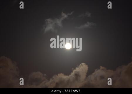 Full moon on the partly cloudy sky at night. Shining moon background photo. Stock Photo