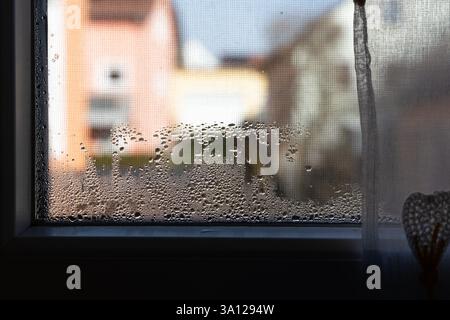 Water droplets and foggy patterns form on a window due to poor ventilation, affecting indoor air quality in a German home. Stock Photo