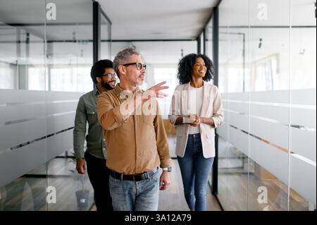 Business executive walking through the office with confident team members. A dynamic corporate environment emphasizing leadership, teamwork, and innovation for business success. Stock Photo