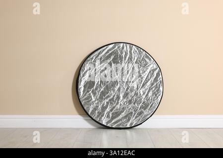 Professional reflector on floor near beige wall. Photo studio equipment Stock Photo