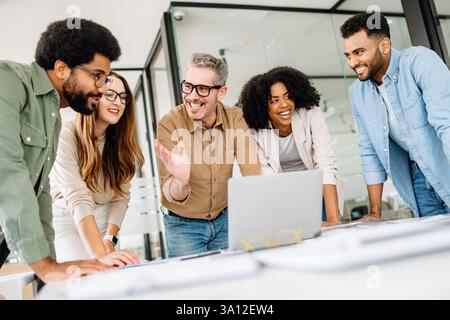 Confident business team working on a strategy at a desk, analyzing financial reports and discussing company growth. A diverse team in a corporate setting collaborating for success and innovatio Stock Photo