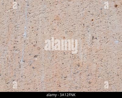 Closeup of a textured beige concrete surface showcases small pebbles fine cracks and delicate white scratches abstract natural background Stock Photo