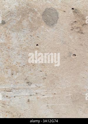 Closeup texture of a weathered textured concrete surface reveals a rustic gray expanse marked by scratches small holes and subtle dark patches Stock Photo