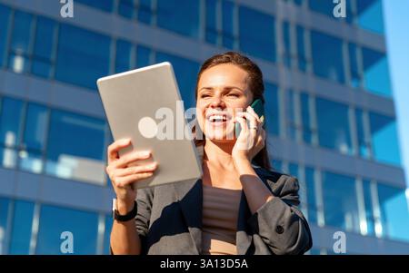 Businesswoman talking on mobile phone while looking at digital tablet Stock Photo