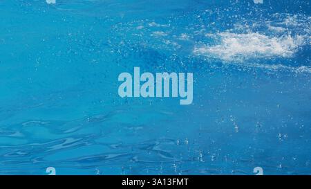 Rippling Blue Water Surface with Splash and Gentle Droplets Stock Photo