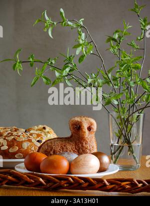 Easter still life containing a small lamb cake, painted eggs, traditional Czech Easter sweet cake called "mazanec", an Easter whip and green twigs Stock Photo