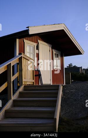Wooden stairs leasing to a typical Swedish red cabin with beautiful golden light at sunset during a summer evening in Orust, Sweden, 2024 Stock Photo
