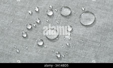 Water drops on a grey water-repellent fabric. Closeup. Stock Photo
