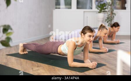 Young woman practicing plank pose in yoga studio Stock Photo