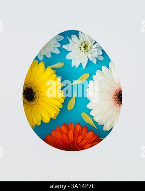 Spring composition with colorful flowers visible through an egg shaped gap on blue background. Minimal Easter concept. Creative festive holiday layout Stock Photo