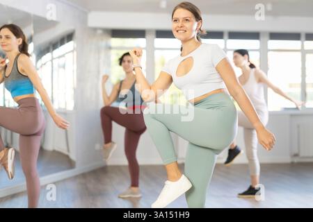 Cheerful young female instructor leading Zumba class for women Stock Photo