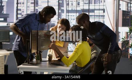 Upset IT workers in office debating, doing brainstorming, looking through lines of code on computer. Team of company employees discussing in workspace, disagreeing with each other, camera A Stock Photo