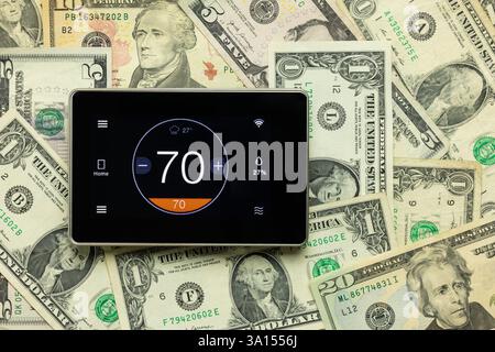Heating and Cooling Costs - A touch screen wifi thermometer surrounded by money. Stock Photo
