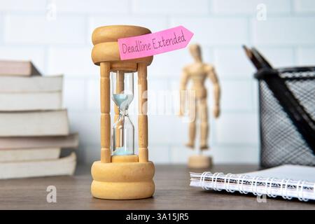 A wooden hourglass and sticky note with the text "Deadline Extended". Time management concept. Stock Photo