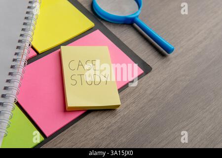 A yellow sticky note with the words "CASE STUDY" alongside a notebook and a magnifying glass. Stock Photo