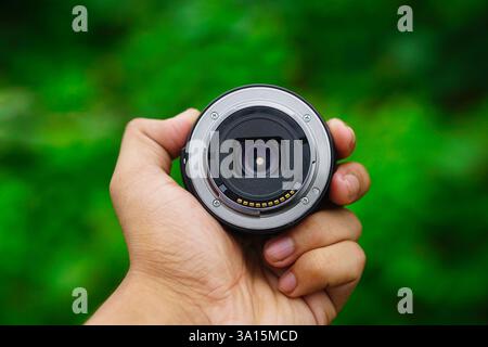 Male hand holding a compact zoom lens and showing lens backside also auto fucus connector lens mount Stock Photo