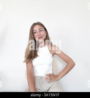 Young woman poses confidently in casual clothing against a neutral background Stock Photo