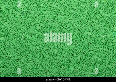 Close-up of uncooked green vermicelli pasta, small cylindrical noodles scattered in a textured background. Detailed food texture ideal for culinary, p Stock Photo