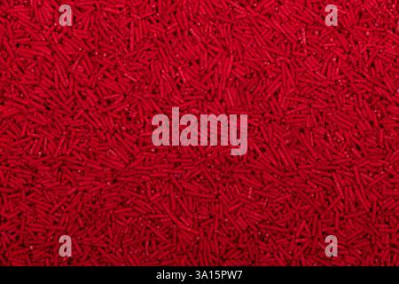 Close-up of uncooked red vermicelli pasta, small cylindrical noodles scattered in a textured background. Detailed food texture ideal for culinary, pac Stock Photo