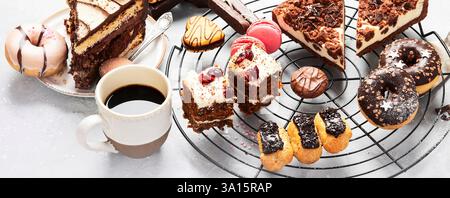 Table with various cookies, donuts, cakes and coffe cups on light backround. Stock Photo