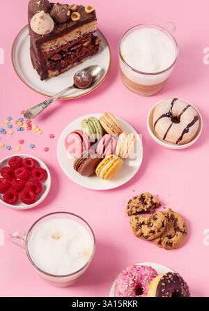 Table with various cookies, donuts, cakes, cheesecakes and coffee cups  on pink background.  Delicious dessert table. Stock Photo