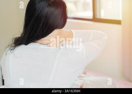 Back view head shot close up adult unhappy woman in bed, waking up in morning, feeling strong neck ache. Copy space. Stock Photo