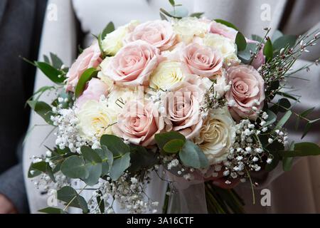 Wedding bouquet of pink and white roses and eucalyptus leaves held by a bride Stock Photo