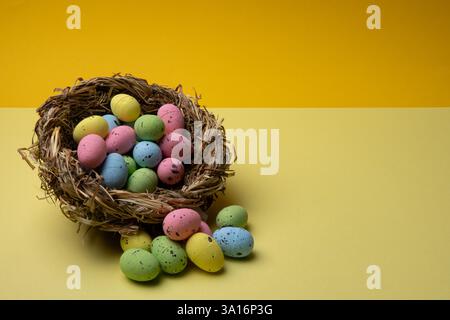 A bird's nest is filled with and surrounded by pastel colored, speckled easter eggs. Stock Photo