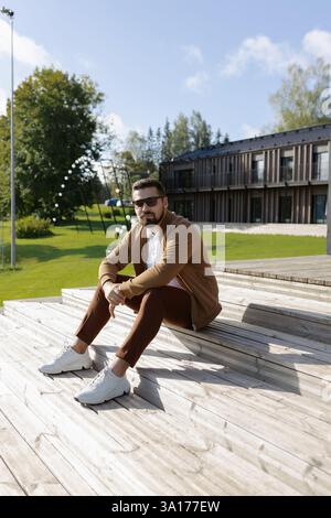 Handsome young adult man sitting on outside terrace stairs Stock Photo
