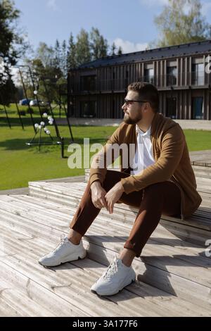Young adult stylish man enjoying sunlight on wooden terrace Stock Photo