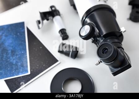 Detail of a telescope eyepiece on a white table with different telescope elements and photographs. Top view. Stock Photo