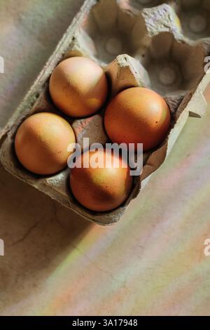 Rainbows shine down on four brown eggs in open egg carton Stock Photo