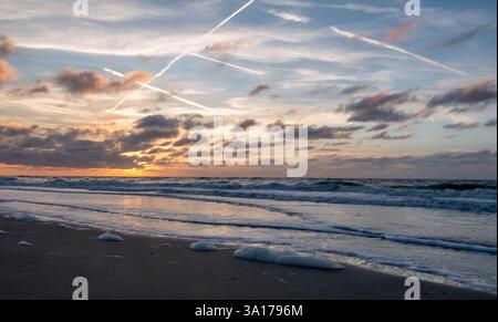 A captivating sunset featuring vibrant colors beautifully reflecting on the calm, serene ocean waters Stock Photo