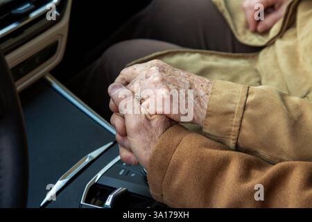 An elderly caucasian couple holding hands in a car Stock Photo