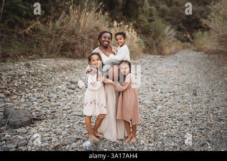 Black pregnant mom boy sitting on belly girls hugging in fields Stock Photo
