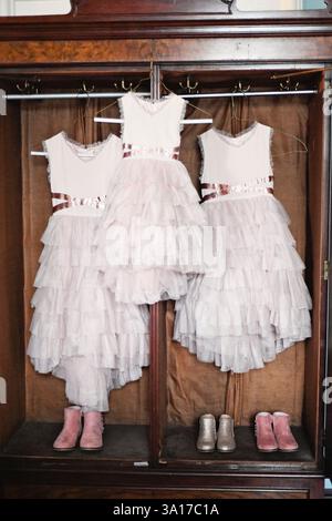 Three ruffled flower girl dresses with matching boots in a vinta Stock Photo