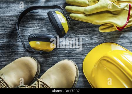Earmuffs protective gloves safety cap boots on wooden board Stock Photo