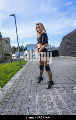 Blonde dancer showcasing high heel and urban dance styles in a vibrant outdoor city setting, radiating energy and confidence Stock Photo