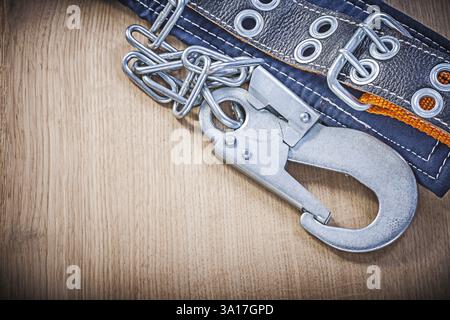 Construction body belt with metal carabiners chain on wooden board Stock Photo