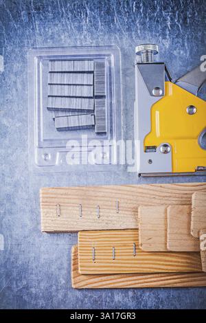 Composition of construction stapler chrome staples wooden building board on metallic background Stock Photo