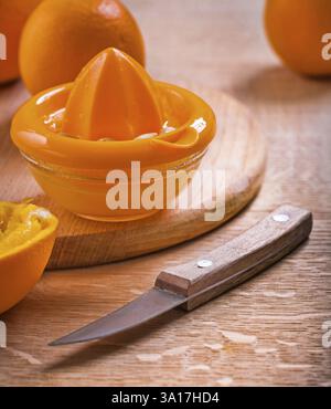 Close up view on orange fruits juicer knife on wooden board Stock Photo