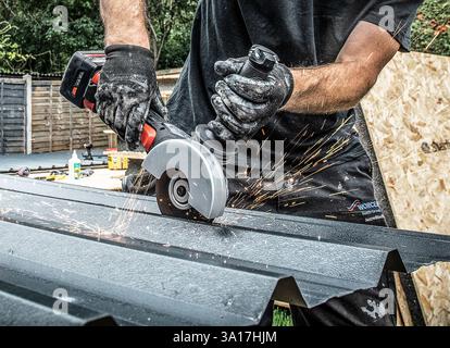 A male metalworker using an angle grinder cutting metal creating a lot of sparks. Stock Photo