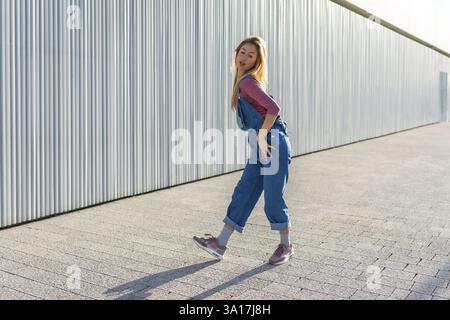Talented young blonde woman dancing urban style outdoors, showcasing her energetic moves and passion for street dance Stock Photo