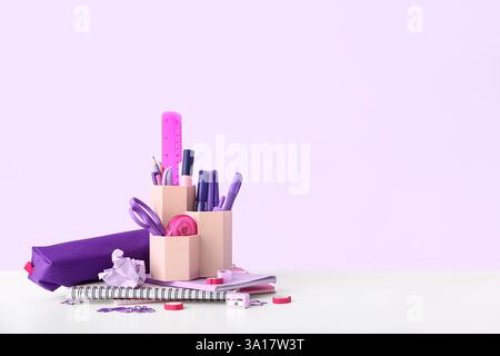 Holder with different stationery and notebooks on light desk Stock Photo