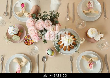 Woman decorating table with roses for Easter celebration. Top view Stock Photo