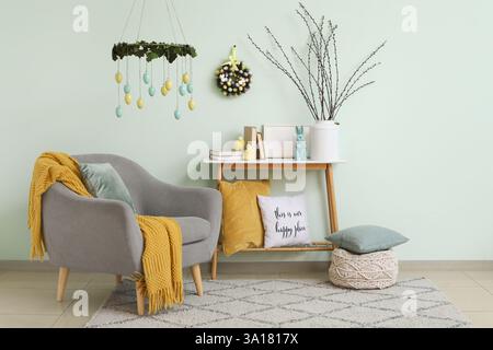 Armchair and table with Easter decorations near blue wall in living room Stock Photo